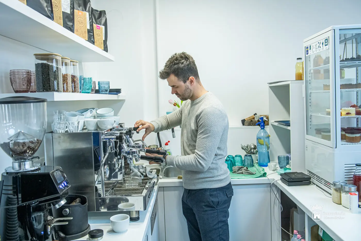 A Mindenem Café pultja kávégéppel és süteményes vitrinnel